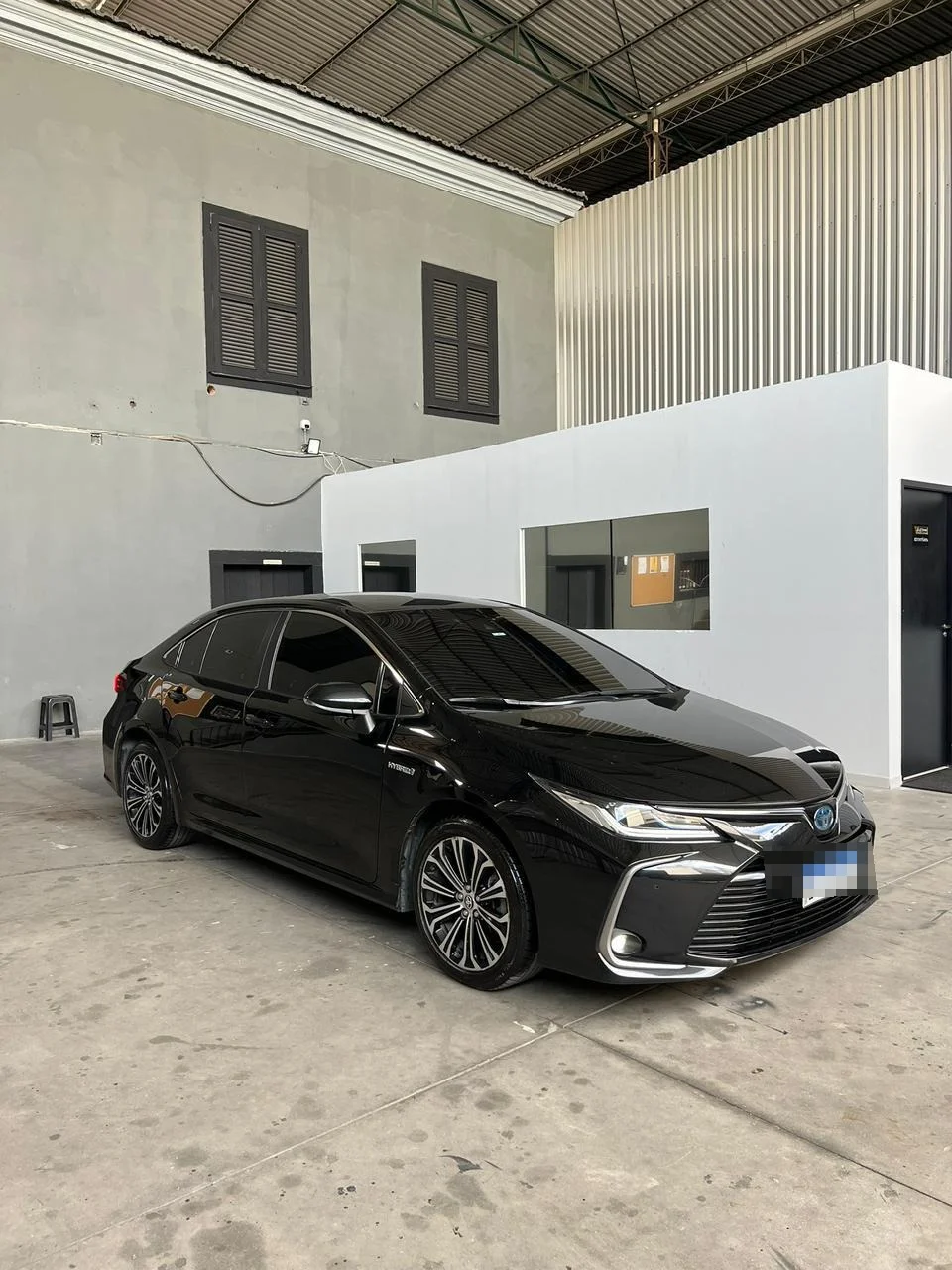 Toyota Corolla híbrido preto, vista frontal em três quartos, disponível para locação sem motorista